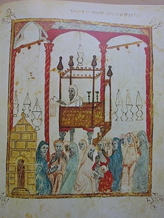 A color image of a Jewish prayer leader, or cantor, reading the Passover story in Islamic Spain. The cantor reads from a bimah, or platform. A crowd is gathered around to listen.